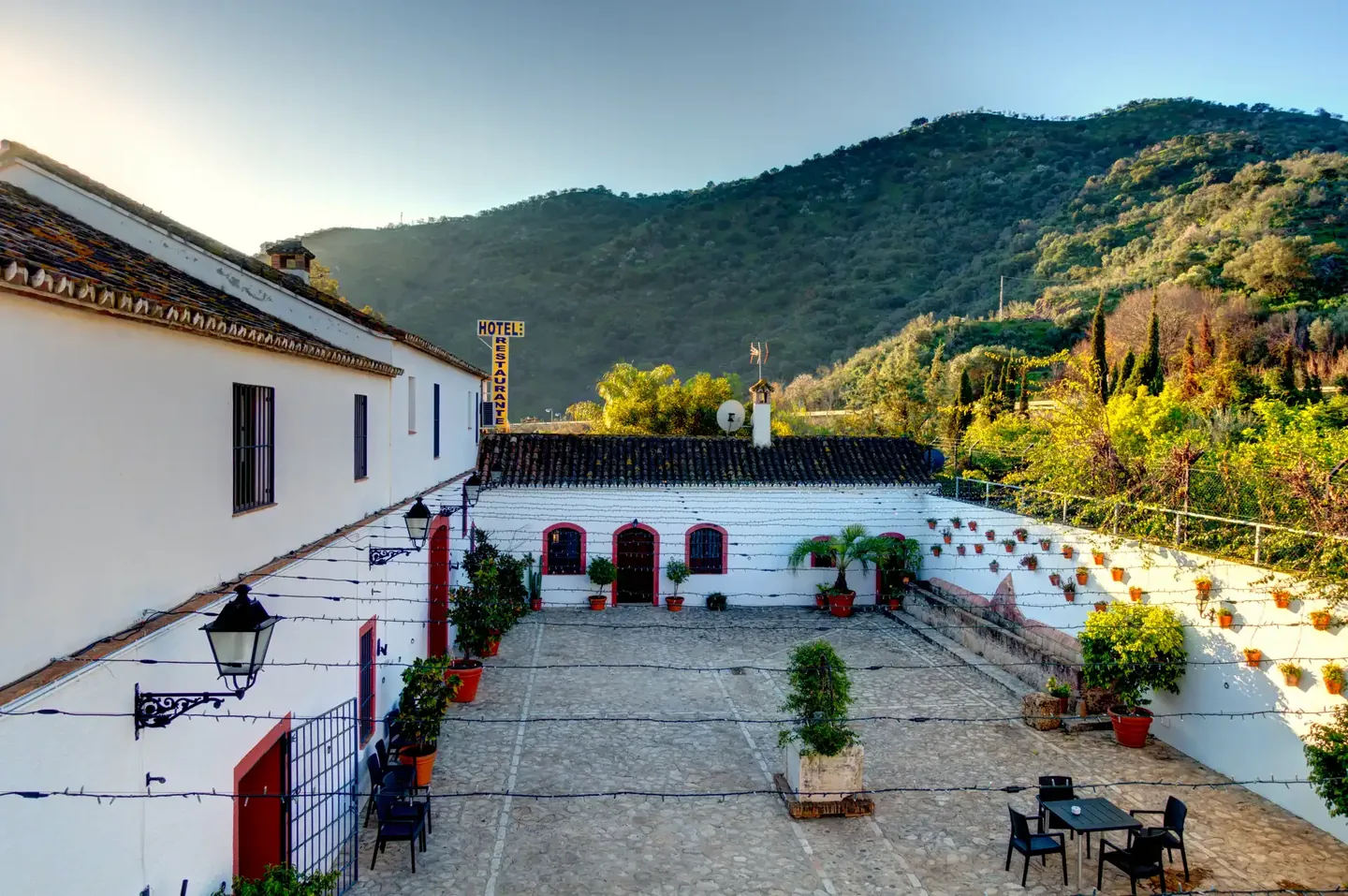 Whitewashed Andalusian courtyard with lanterns and green mountains behind