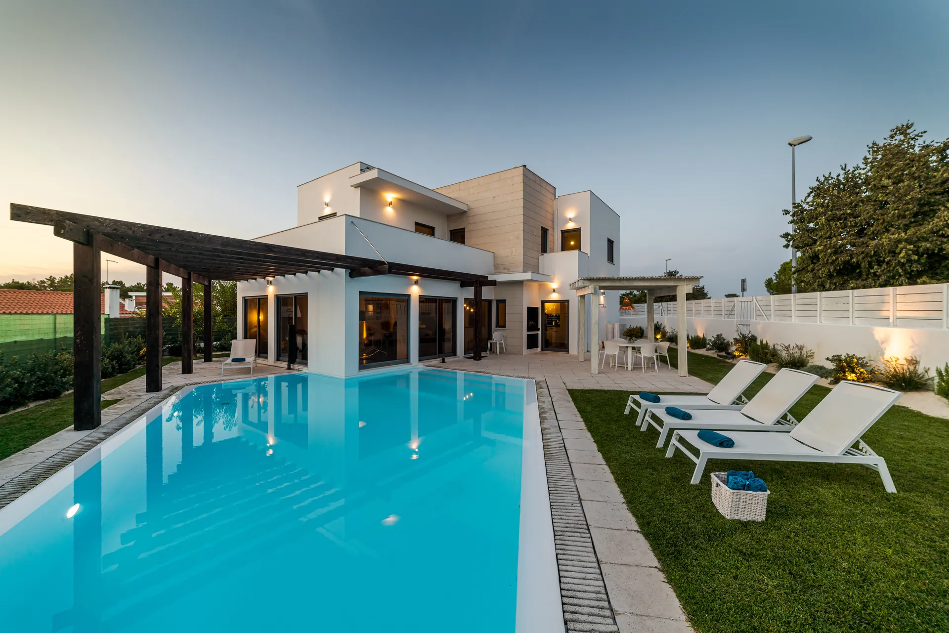 Modern white villa with a long pool, pergola and lawn