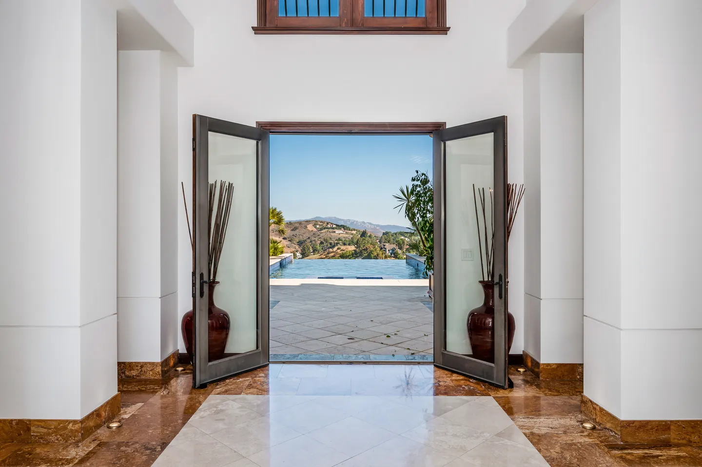 Tall double doors opening from a white hall onto the pool terrace