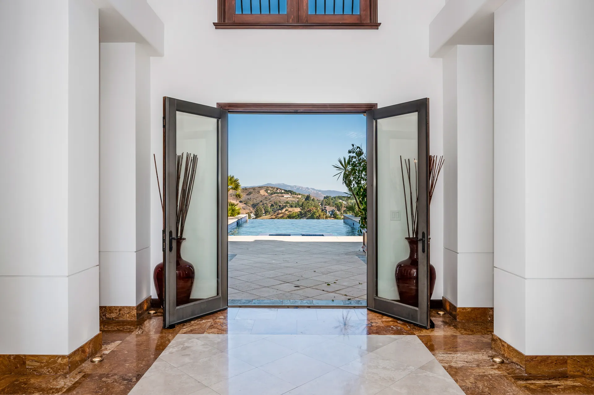 Tall double doors opening from a white hall onto the pool terrace