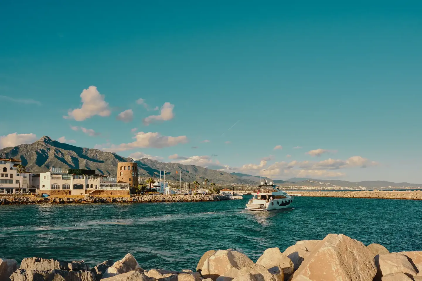 A yacht leaving Puerto Banús with La Concha and the Sierra Blanca behind