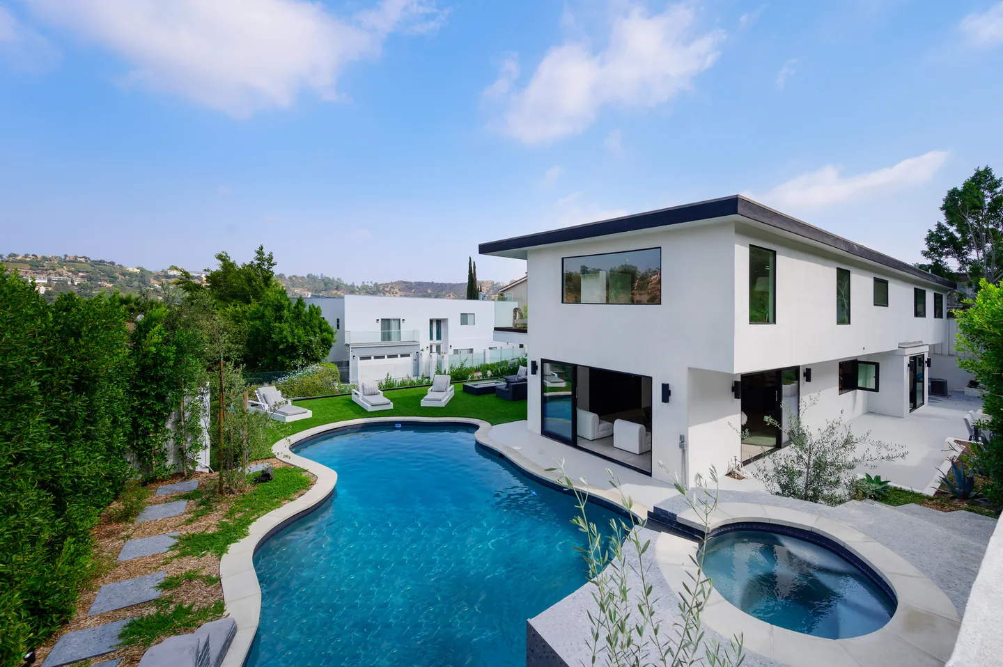 White villa with a curved pool among mature trees