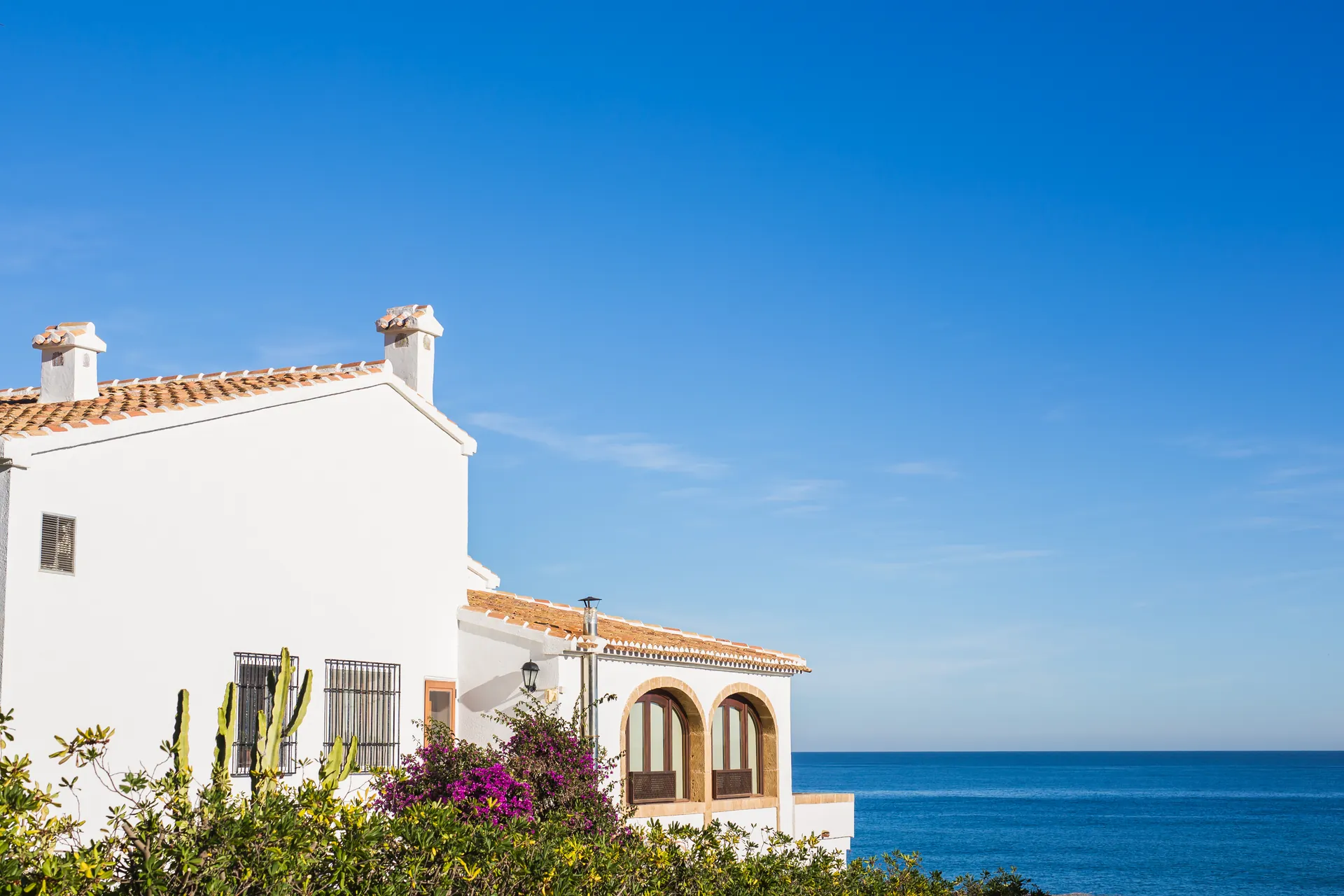 White Mediterranean villa with arches and chimneys against the sea